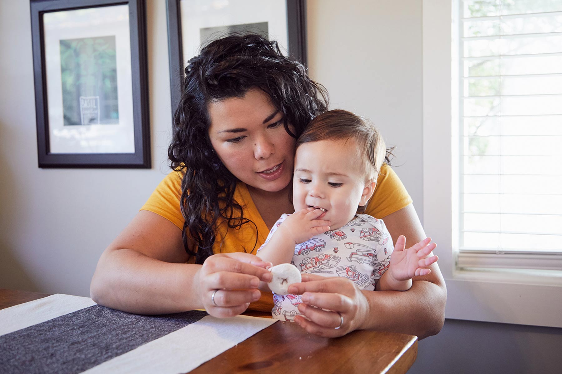 mom breaking off piece of doughnut for 9 month old